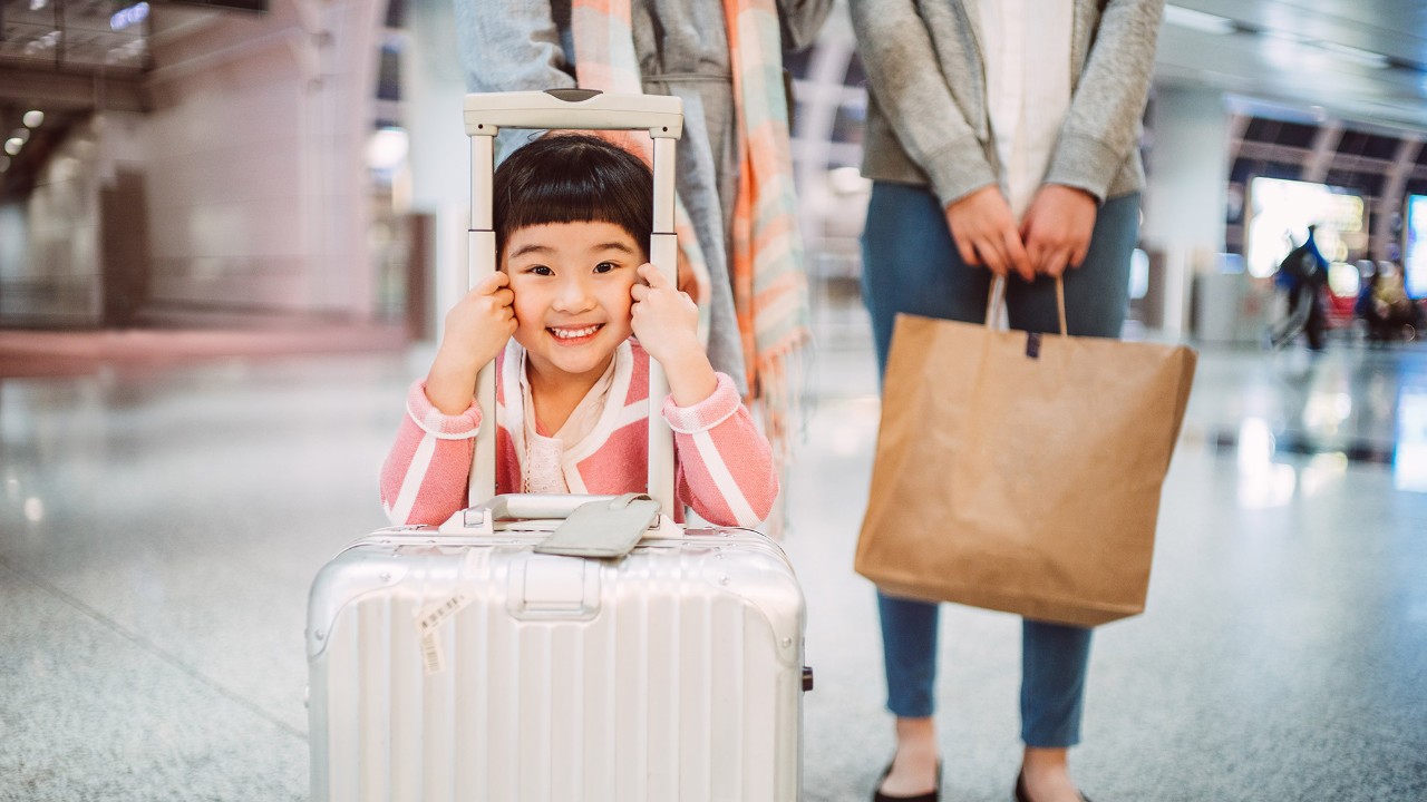A little girl smiling with a suitcase; image used for HSBC Malaysia Visa Signature Credit Card page.