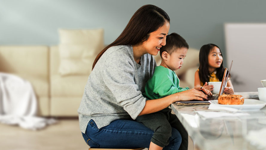A mother is using laptop with her son in the living room; image used for HSBC Malaysia Everyday Global Account page.