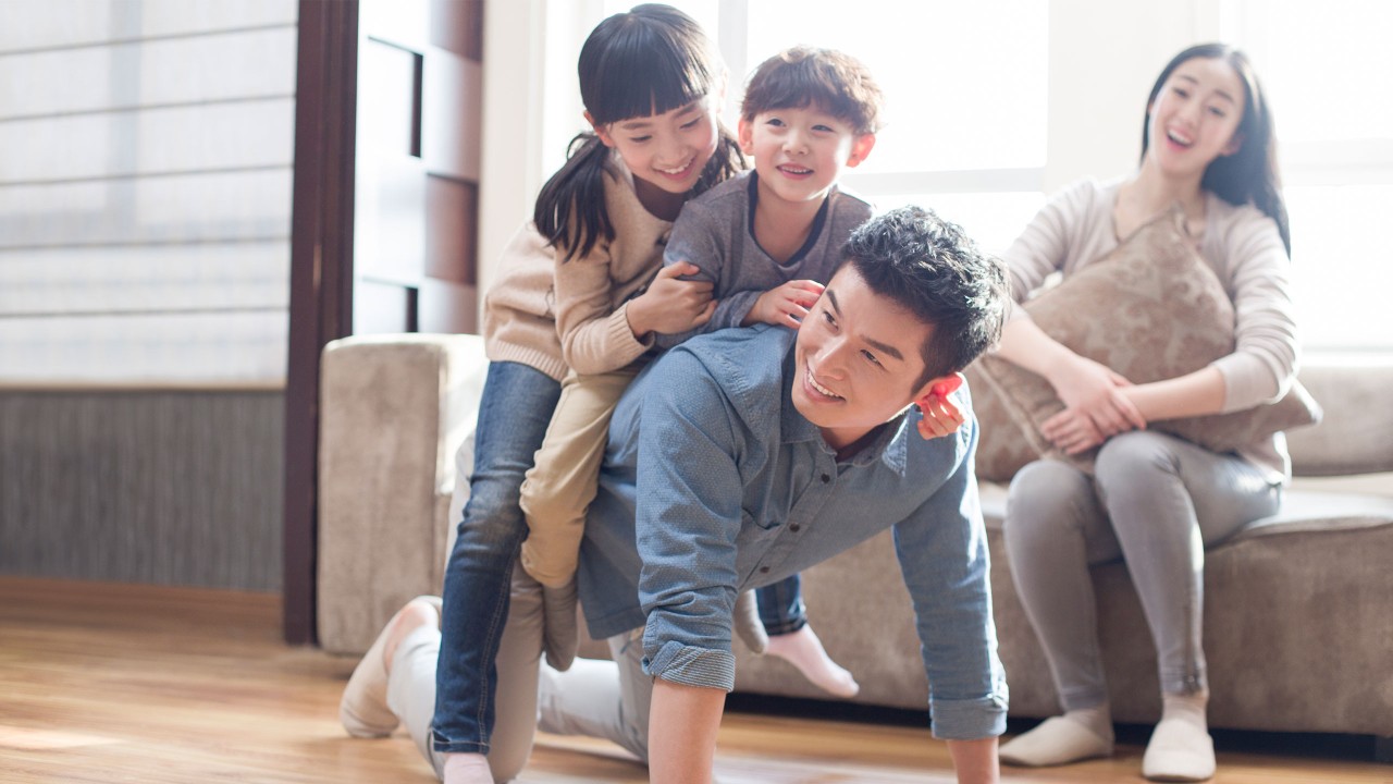 Happy family is playing piggyback ride at home; image used for HSBC Malaysia Cash Instalment Plan page.