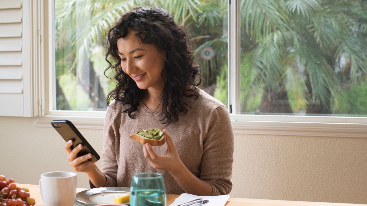Woman eating breakfast while on phone; image used for HSBC MY getting into a savings habit article page