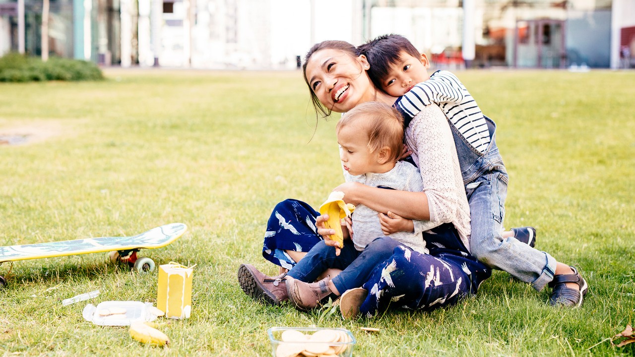 A mother playing with her children on the grass; image used for HSBC Malaysia HealthPlus Plan page.