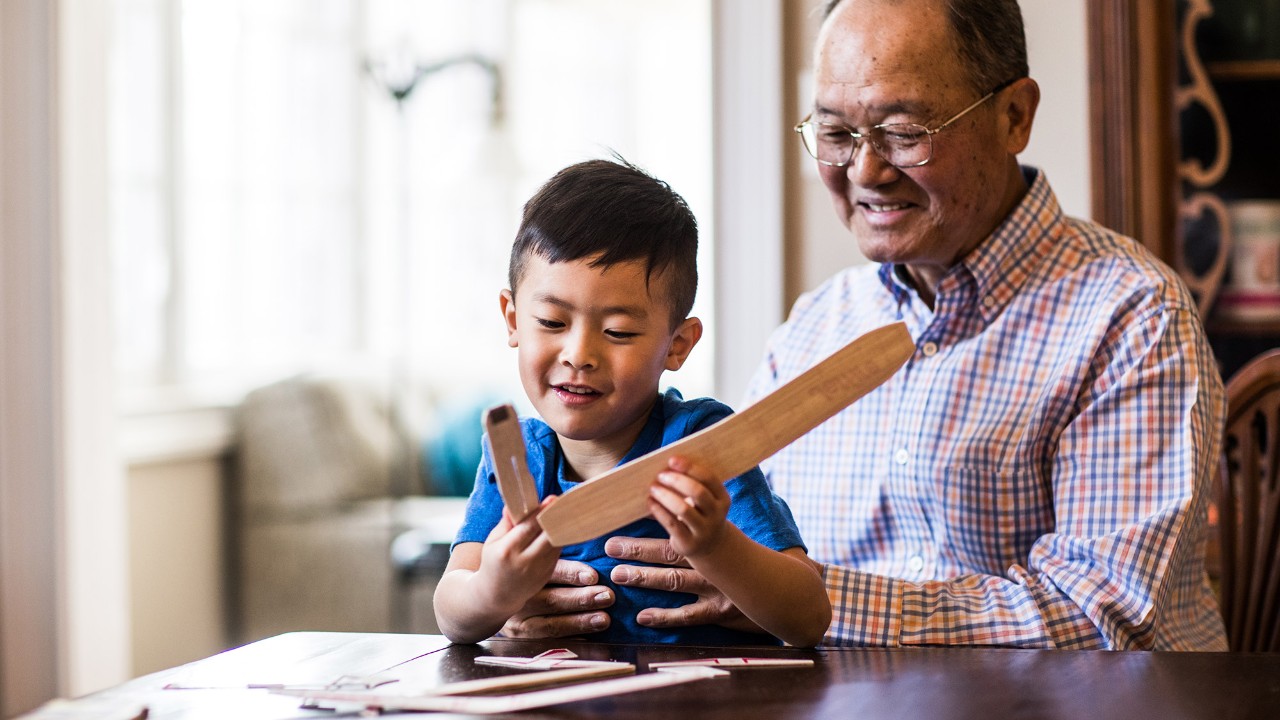 A grandfather playing with his grandson's toy; image used for HSBC Malaysia UniversalLegacy Plan page.