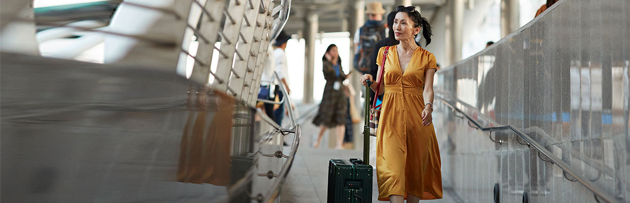A woman is walking on the street with a luggage; image used on HSBC Malaysia travel care page.